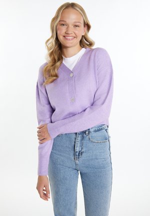 Cardigan liliac cu decolteu în V, cu două butoane și mâneci lungi. Purtați peste un tricou alb, asortat cu blugi albaștri cu talie înaltă.