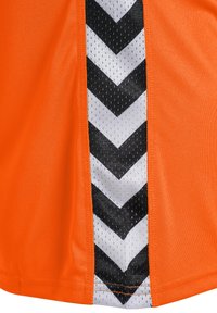 Orange träningsskjorta med en sidopanel i svart och vitt chevronmönster. Tyget är mjukt och ventilerande med en lätt lyster.