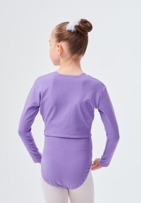 Lila Langarm-Body mit slim Fit, glatter Textur und hohem Rückenteil. Getragen mit hellen Strumpfhosen und einem dekorativen Haarschmuck.