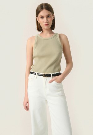 Débardeur côtelé vert olive au design ajusté, associé à un jean blanc taille haute et une ceinture noire avec une boucle en or.