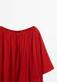 Blouse rouge à décolleté bateau avec encolure élastique et tissu ample froncé s'étendant jusqu'aux larges manches sur fond blanc.