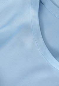 Světlomodrá látka s hladkým povrchem, s kulatým výstřihem a pečlivě ušitými okraji, která ukazuje jemný, splývavý design.