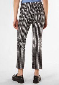 Czarno-białe spodnie w jodełkę z krótki krojem, o gładkiej fakturze, noszone z czarnymi butami na platformie.