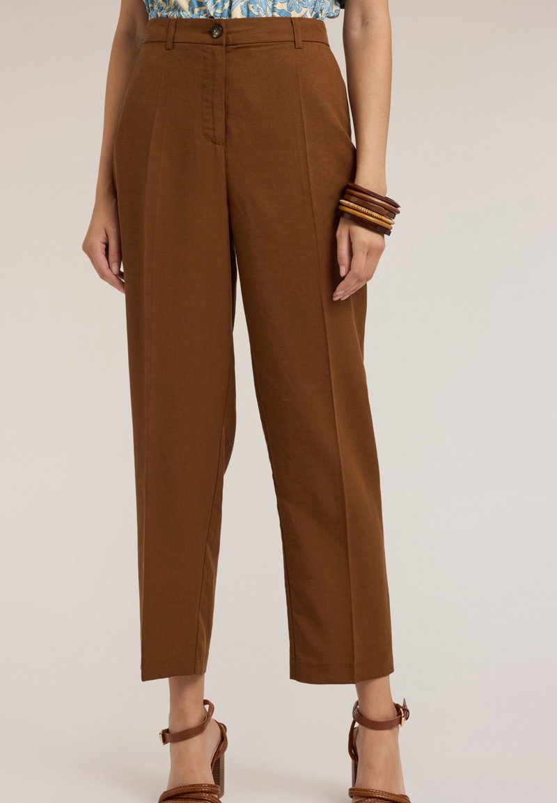 Pantalons marron taille haute avec une coupe droite, présentant des détails de pli avant et une fermeture à bouton assortie. Texture de tissu lisse.