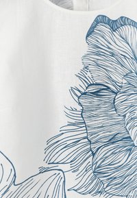 Tissu blanc avec un dessin linéaire bleu détaillé d'une grande fleur, montrant des pétales et des motifs fins semblables à des veines sur le textile.