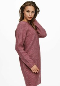 Rosa ribbad klänning med lång ärm, med en texturerad yta och en något lös design, lämplig för avslappnad användning.