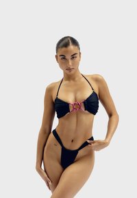 Černý bikinový set s nabíraným designem, zvýrazněný růžovou kovovou sponou vpředu, s vysokým střihovým stylem spodního dílu.