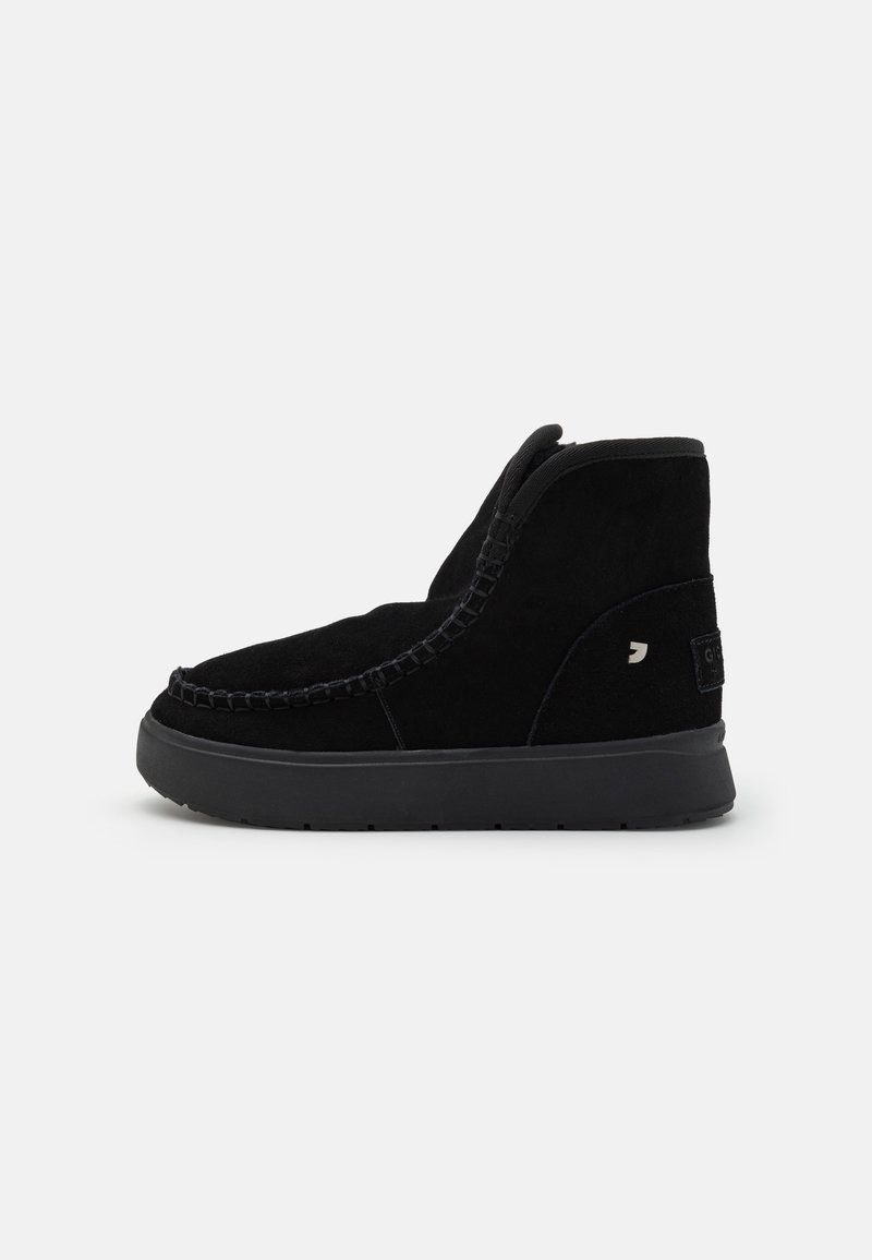 Schwarze Wildleder-Stiefeletten mit abgerundetem Zeh, feinen Nähten, seitlichem Einsatz und einer strukturierten Gummisohle. Kleines Logodetail auf der Rückseite.