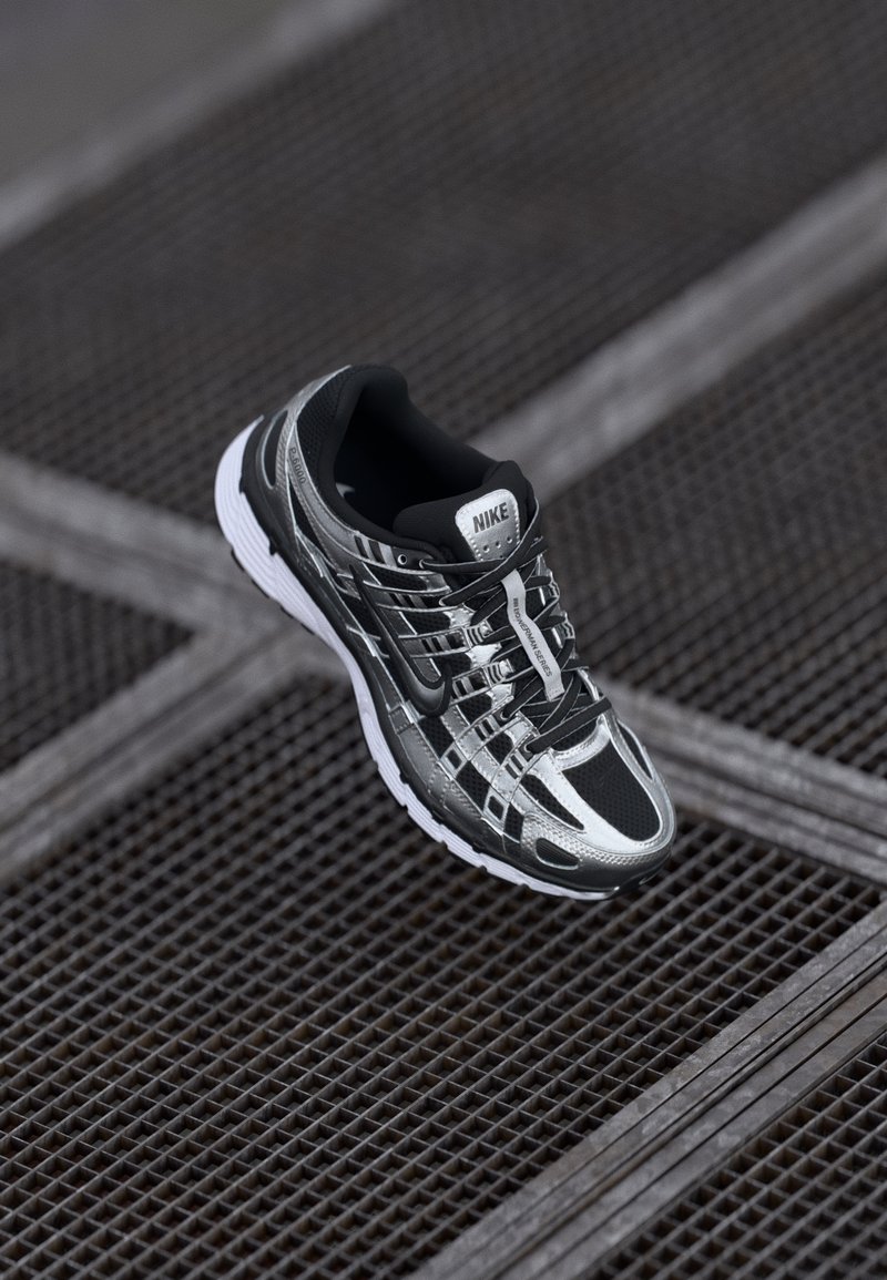 Scarpa da corsa Nike con una combinazione di colori nera e argento, tomaia in rete, suola testurizzata e sistema di allacciatura per una vestibilità sicura.