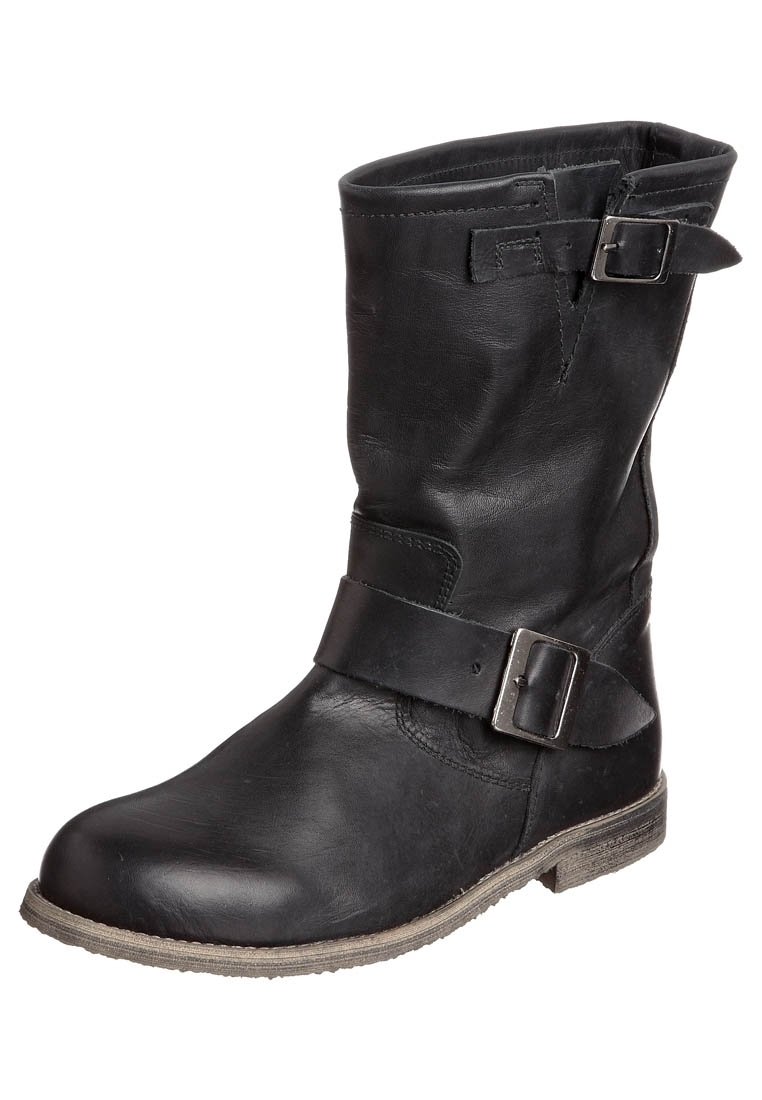 Bottine en cuir noir avec un bout rond, détail de boucle sur le côté et un talon bas. La surface texturée présente une finition légèrement vieilli.