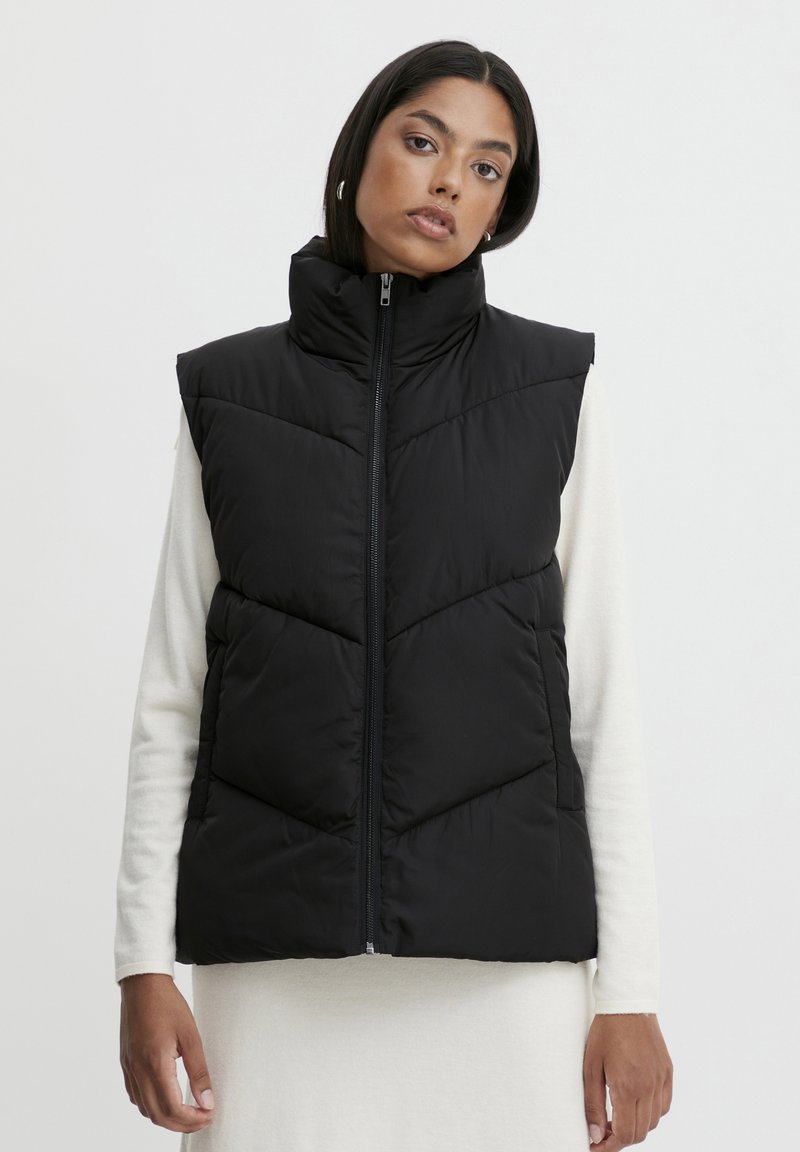 Gilet rembourré noir avec un col montant, fermeture éclair et motif en chevrons. Fabriqué en tissu léger, il présente une texture lisse et un design sans manches.