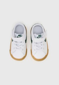 Fehér sneaker zöld részletekkel, sima felsőrésszel, fehér fűzőkkel, tépőzárral és barna gumitalppal.