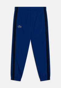 Pantaloni sportivi blu realizzati in materiale leggero, con vita elastica, pannelli in rete laterali e un piccolo logo ricamato sul fronte.