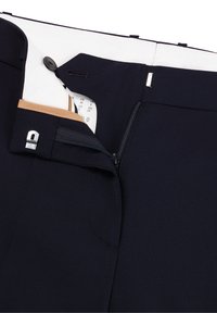 Los pantalones de marina cuentan con una cremallera frontal, cierre de botón y un forro interno parcialmente visible con un bolsillo. La tela es suave y estructurada.