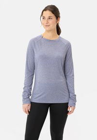 Langärmliges Sportoberteil aus hellblauem Stoff mit glatter Textur, Rundhalsausschnitt und Daumenlöchern an den Bündchen. Kombiniert mit schwarzen Leggings.