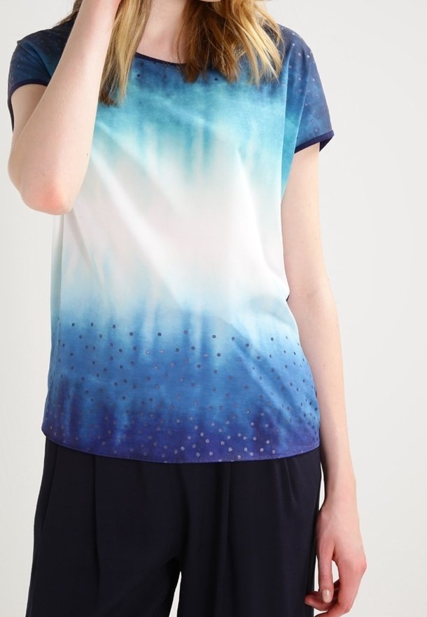 Blusa de manga corta, con un degradado de blanco a azul, presenta una tela suave con un estampado de puntos cerca del dobladillo. Ribete en color marino en el escote y las mangas.