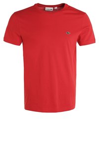 Camiseta de algodón roja con cuello redondo, mangas cortas y un pequeño logo de cocodrilo verde en la parte izquierda del pecho.