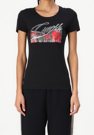 Zwart, nauwsluitend T-shirt met korte mouwen, voorzien van een met strasssteentjes bezet "Guess"-logo, een rode roosgrafiek en de tekst "Established 1981" op de voorkant.