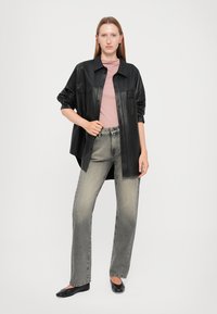 Camisa oversized de cuero negro, top ajustado rosa claro, vaqueros de pierna ancha grises, bailarinas negras. Texturas suaves, diseño casual, paleta de colores neutros.