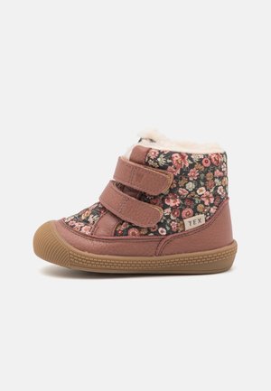 Botte d’hiver enfant rose à motif floral avec deux bandes velcro, semelle en caoutchouc et doublure douce en polaire blanche.
