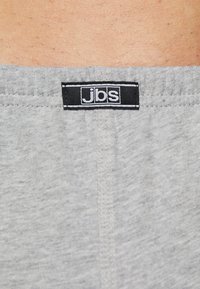 Grau gefärbter Stoffbund mit einem schwarzen Etikett, auf dem in weißer Schrift "jbs." steht. Weiche Textur mit glatter Oberfläche und sichtbaren Nähten.
