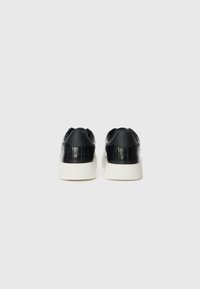 Black leather sneakers with crocodile texture and smooth accents, featuring a white rubber sole. The back shows padded collar details.