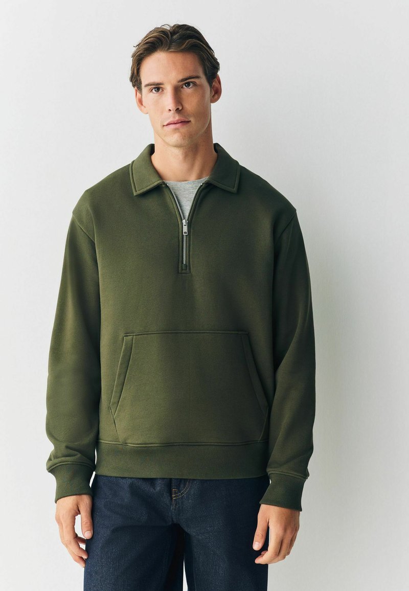 Olijfgroene pullover sweatshirt met een kwart-rits hals, voorste kangoeroezak en geribbelde manchetten. Zachte stof en een ontspannen pasvorm.