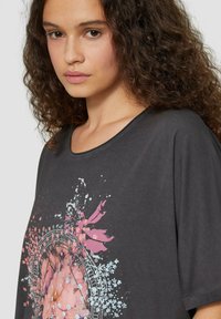 Lässiges, dunkelgraues T-Shirt aus weicher Baumwolle, das mit einem bunten Blumen-Design und einem runden Halsausschnitt mit kurzen Ärmeln versehen ist.
