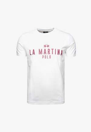 Valkoinen puuvillapaita, jossa on punainen "LA MARTINA POLO" -logo ja kaksi ristiin olevia polo-mailoja tekstin alla. Yksinkertainen pyöreä kaula-aukko.