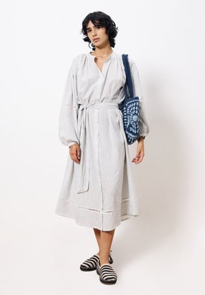 Gestreepte, button-down jurk met lange mouwen en een tailleband. Lichtgewicht stof, tot onder de knie, gecombineerd met een blauwe haaknaalden tas en gestreepte schoeisel.