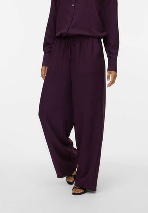 Pantalons larges violets avec une taille à cordon, deux poches avant et un tissu texturé. Assortis avec des sandales noires.