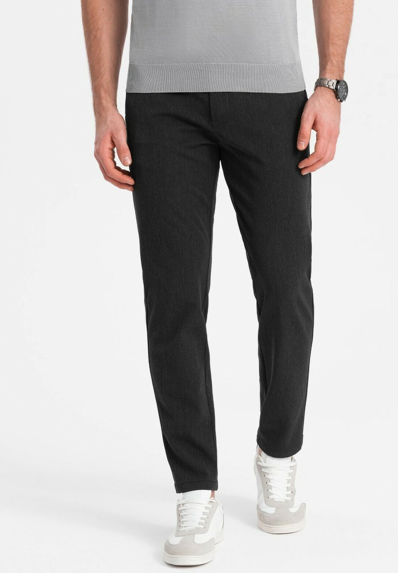 Donkergrijze slim-fit broek met een gladde textuur, gecombineerd met casual witte en grijze sneakers. Geschikt voor dagelijks gebruik.