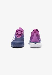 Scarpe sportive viola con una superficie liscia, caratterizzate da un design a gradiente, lettera bianca e una suola bianca imbottita.