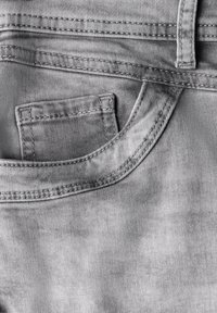 Szary denim o gładkiej fakturze z przednią kieszenią i detalami w postaci szwów. Powierzchnia jest gładka z lekkim połyskiem, a design jest minimalistyczny.