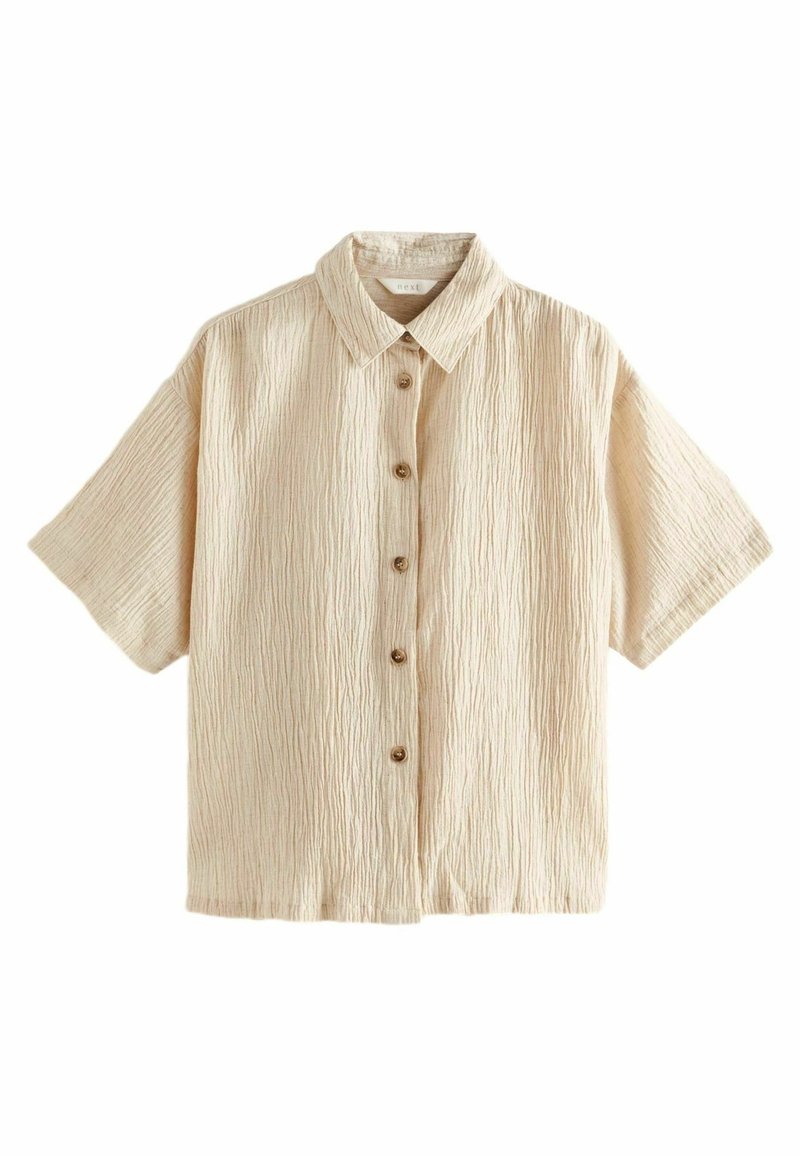 Chemise beige à manches courtes avec texture froissée, col et six boutons marron sur le devant.