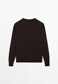 Maglione lungo a maniche con scollo rotondo, di colore marrone scuro. Maglia morbida e testurizzata con polsini e orlo a costine. Design semplice e minimalista.