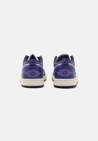 Des baskets en cuir violet avec une semelle crème, des accents blancs et un logo Air Jordan brodé sur le talon. Texture lisse et design bas.