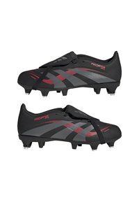 Schwarze Fußballschuhe mit einem synthetischen Obermaterial, strukturierter Oberfläche, roten Akzenten und ausgeprägten grauen Streifen; entwickelt für Traktion und Agilität.