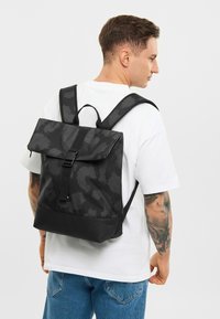 Rucsac negru cu model, cu închidere prin clapetă, curele reglabile și finisaj mat. Material durabil cu un design elegant și minimalist.