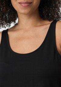 Top senza maniche nero con scollatura rotonda, realizzato in tessuto morbido, con cuciture sottili lungo i bordi.
