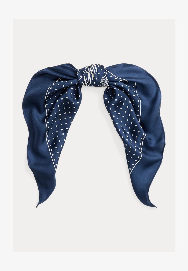 Tmavomodrý hodvábny šál s bielymi bodkami a tenkými okrajovými líniami, zložený a voľne zviazaný na bielom pozadí.