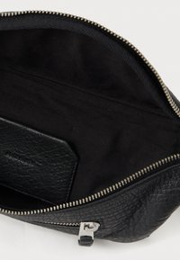 Clutch de couro preto com uma superfície texturizada, fecho de zipper de metal e um interior liso preto. Apresenta um pequeno porta-cartões de couro no interior.