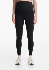 Fekete, magas derekú leggings, rugalmas anyagból készült, sima felületű és varrás nélküli kialakítással a kényelem és a támogatás érdekében.