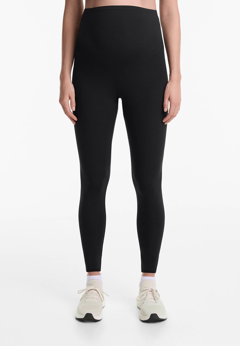 Fekete, magas derekú leggings, rugalmas anyagból készült, sima felületű és varrás nélküli kialakítással a kényelem és a támogatás érdekében.