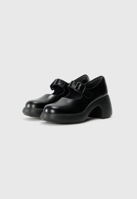 Black leather shoes with a rounded toe, adjustable strap with buckle, and a chunky, curved heel. Smooth texture with a polished finish.
