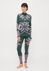 Grønn og rosa strikket termisk sett med geometriske mønstre, en hettegenser med glidelås og tettsittende legginger med teksturerte detaljer.