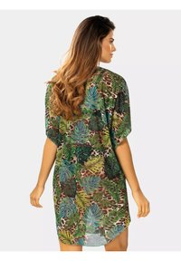 Lekka, luźna sukienka z wyrazistym wzorem zielonych liści na brązowym tle. Krótkie rękawy i zaokrąglony dół. Miękka tekstura.
