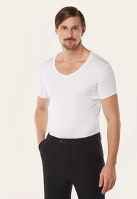 Witte korte mouwen V-hals t-shirt, slim fit, gladde stof. Gecombineerd met zwarte broek met knoopsluiting en zijzakken.