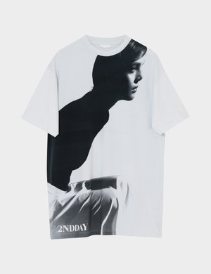 T-shirt blanc avec une photo de profil en noir et blanc d'une personne assise, tournée vers la droite, portant un pantalon blanc, avec le texte "2NDDAY" en bas.