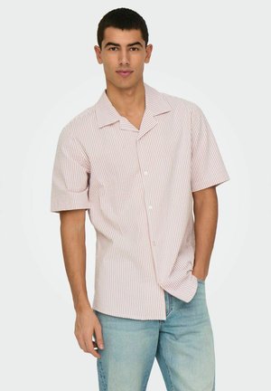 Kortærmet skjorte i lys pink med hvide lodrette striber, knaplukning, spredt krave og afslappet pasform. Båret med lyseblå jeans.